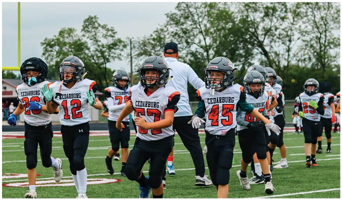 A football game is taking place on a field with players wearing blue and white uniforms. Description generated by AI