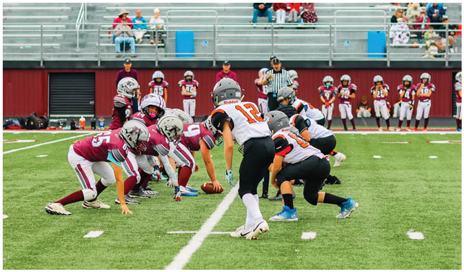 A football game is taking place on a field with players wearing blue and white uniforms. Description generated by AI