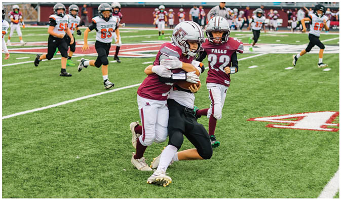 A football game is taking place on a field with players wearing blue and white uniforms. Description generated by AI
