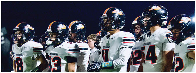 A football game is taking place on a field with players wearing blue and white uniforms. Description generated by AI