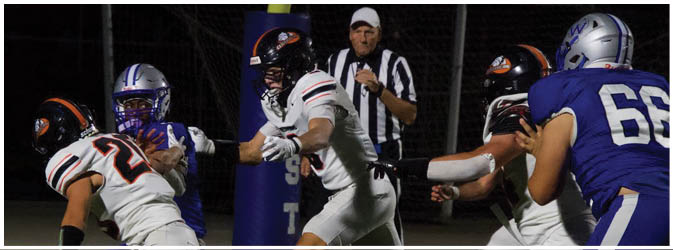 A football game is taking place on a field with players wearing blue and white uniforms. Description generated by AI