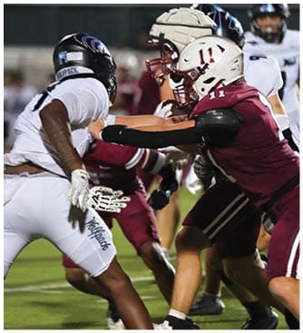 People in football uniforms are actively engaged in a play on a grassy field during a game. Description generated by AI