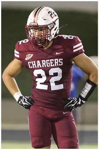 A person wearing a maroon football uniform with the word Chargers and the number 22 on the jersey is captured mid-action on the field. Description generated by AI