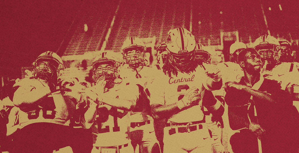 A group of people in football uniforms and helmets stand together on a field with stadium seats in the background. Description generated by AI