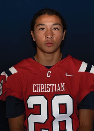 A young man wearing a white and black jersey with the number 14 on it. Description generated by AI