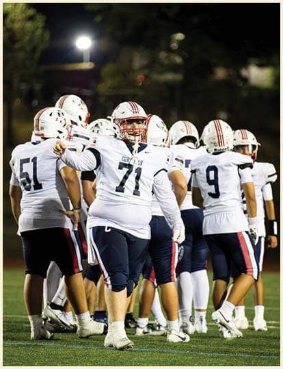Three men wearing green and white uniforms are standing on a field. Description generated by AI