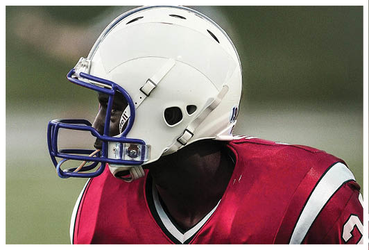 A football player wearing a helmet and a red jersey with the number 24. Description generated by AI