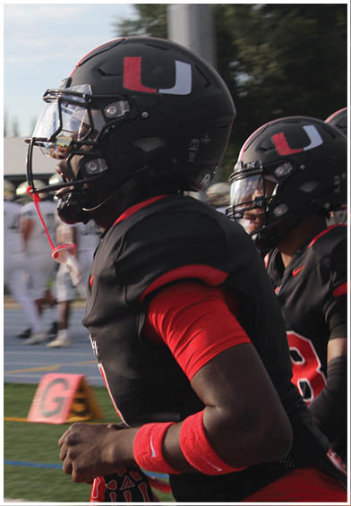 A football player wearing a blue and red jersey. Description generated by AI