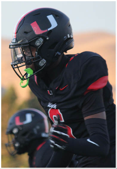 A football player wearing a blue and red jersey. Description generated by AI