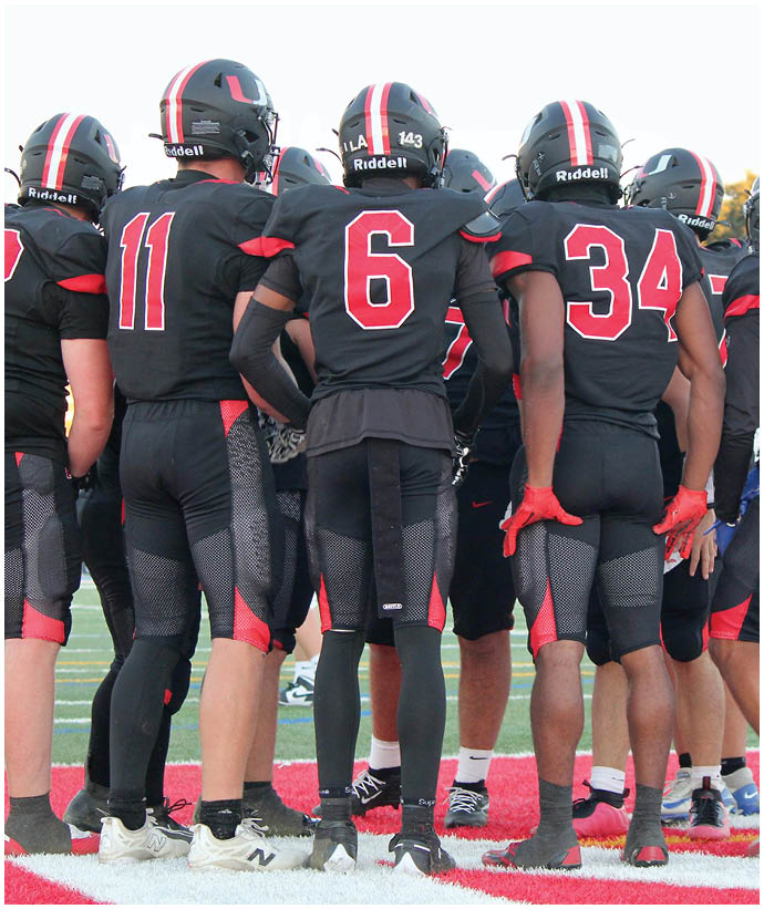A group of football players wearing black and white uniforms. Description generated by AI
