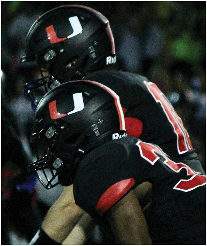 A group of football players wearing black and white uniforms. Description generated by AI