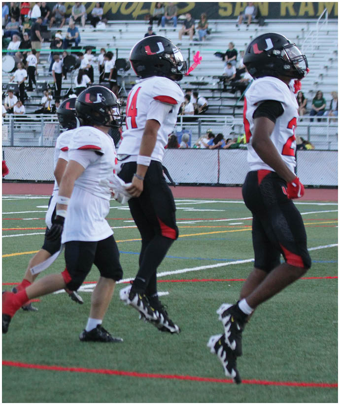 A group of football players wearing black and white uniforms. Description generated by AI