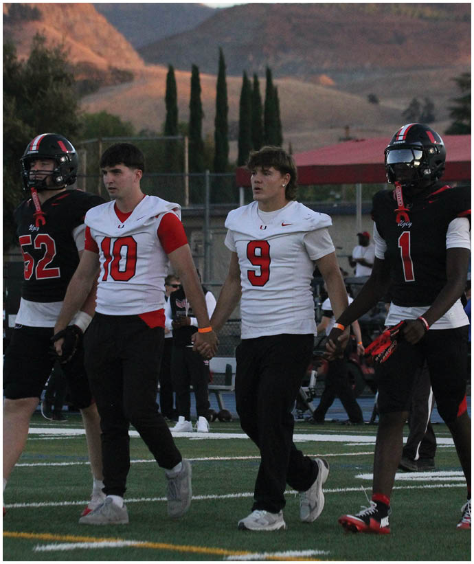 A group of football players wearing black and white uniforms. Description generated by AI