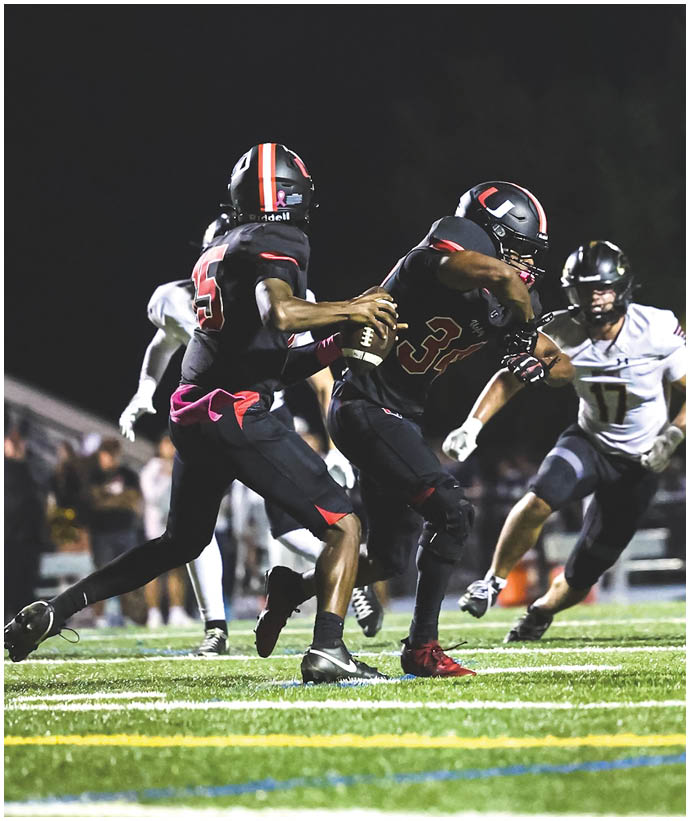 A group of football players wearing black and white uniforms. Description generated by AI