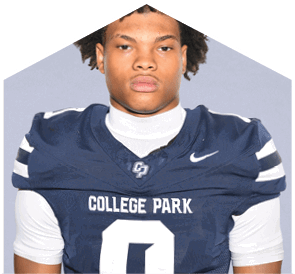 A person with curly hair wearing a dark blue football jersey with the words “College Park" and the number zero stands against a plain light background. Descripci n generada con IA