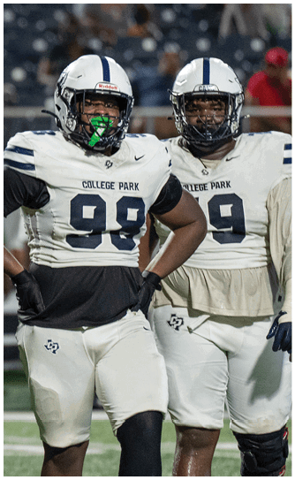 A person wearing a College Park football uniform with the number 99 stands on a field with hands on hips during a game. Descripci n generada con IA