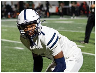 Two people in football uniforms are positioned on a field, appearing ready for a play during a game. Descripci n generada con IA