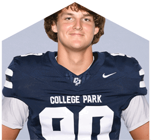 A person with short, tousled hair is wearing a dark blue football jersey with the number three and the words College Park on the front. Descripci n generada con IA
