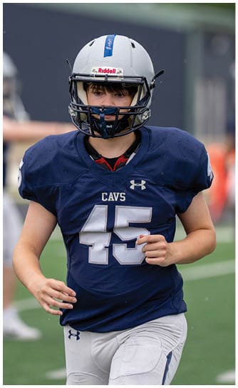 A person wearing a blue football jersey with the number 45 and a white helmet is standing outdoors. Descripci n generada con IA