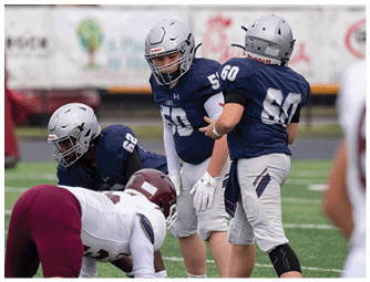 Three people in football uniforms with helmets are actively engaged in a game on a field with others in the background. Descripci n generada con IA