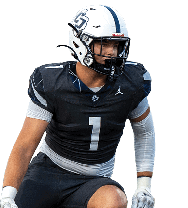 A person wearing a black football uniform with the number one is crouched in an athletic stance on a green field. Descripci n generada con IA