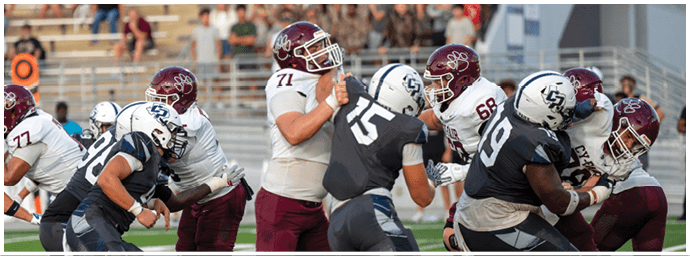 People wearing football uniforms are engaged in a play on a field with some players blocking and others attempting to tackle. Descripci n generada con IA