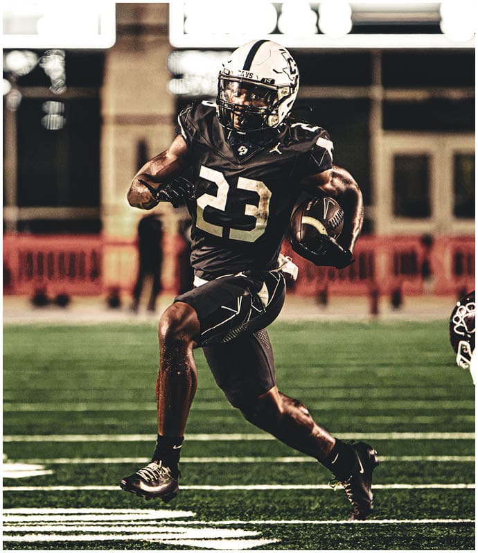 A group of people in football uniforms are engaged in a game on a field with one person holding a football and preparing to throw it. Descripci n generada con IA