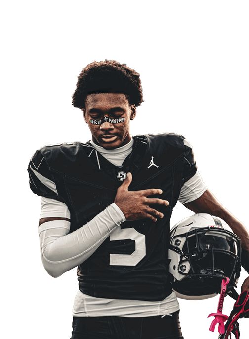 A person wearing a black football uniform with the number five and holding a helmet stands on a field with a hand placed over their chest. Descripci n generada con IA
