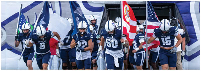A group of people in sports uniforms run forward holding various flags while emerging from a tunnel. Descripci n generada con IA