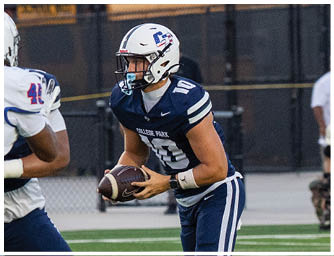 Two people in football uniforms are engaged in a play on a field, with one holding the ball and the other attempting to block or tackle. Descripci n generada con IA