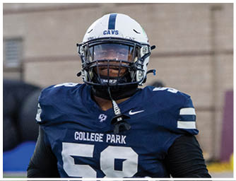 A person wearing a blue football jersey with the number 58 and the words College Park, along with a white helmet labeled CAVS, is standing outdoors. Descripci n generada con IA