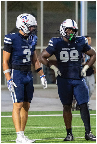 A person wearing a navy blue football uniform with the number seven and a white helmet is crouched on a football field. Descripci n generada con IA