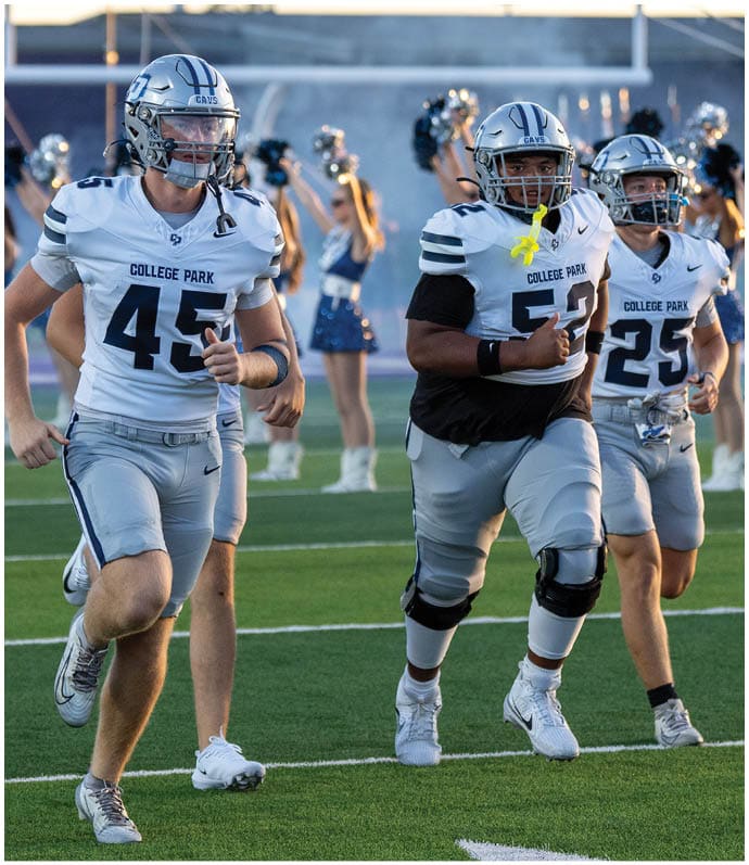 A person wearing a blue and white football uniform with the number 54 and a helmet is standing in front of other similarly dressed people on a field. Descripci n generada con IA