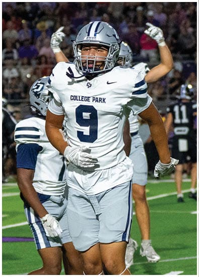 A person wearing a football uniform with the number 4 and a white helmet stands on a field with hands on hips. Descripci n generada con IA