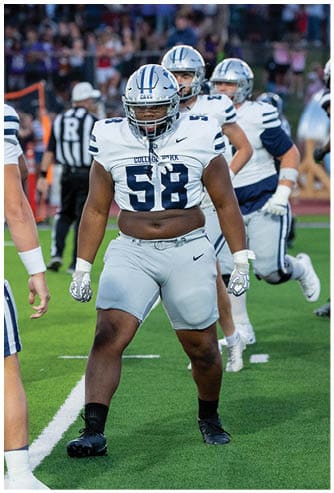 A person wearing a black and white football uniform and helmet is standing outdoors with a blurred background. Descripci n generada con IA