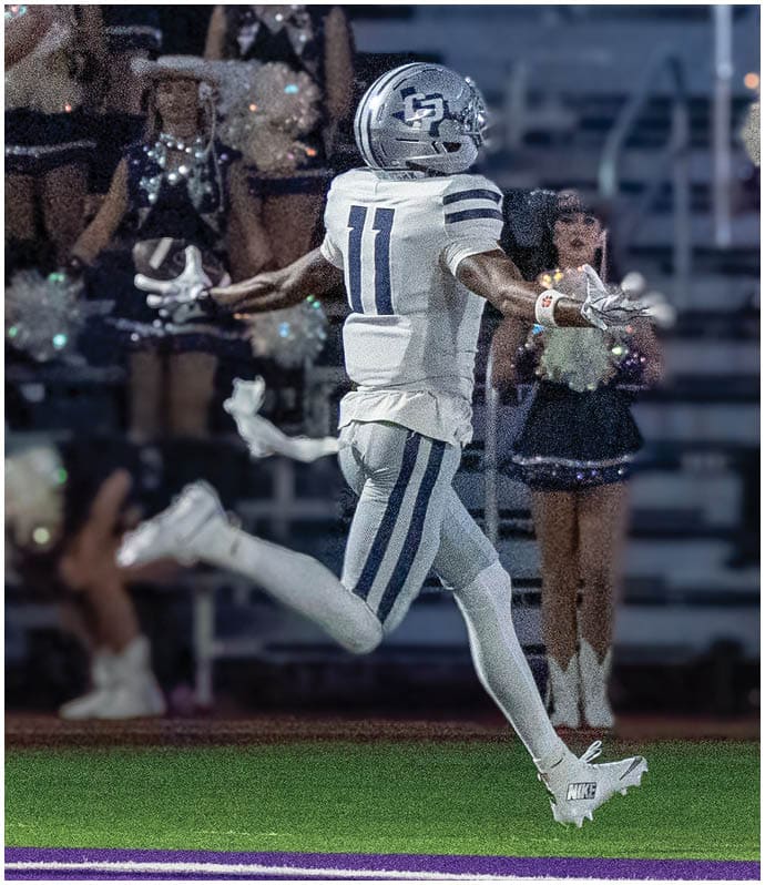 A person wearing a dark football uniform with the number 23 is running with the ball on a football field while other players in dark and white uniforms are nearby. Descripci n generada con IA