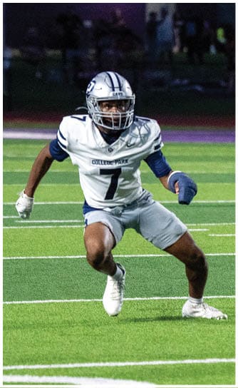 A person wearing a black and white football uniform with the number 50 is actively engaged in a play on a football field with other players around. Descripci n generada con IA
