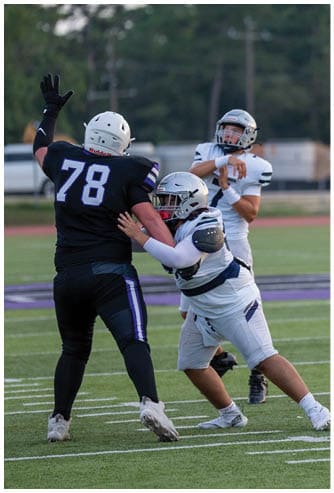 A person wearing a black helmet and a white football uniform with “Bishop Verot" on the jersey is running on a field with another player blurred in the background. Descripci n generada con IA