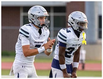 Three people in football uniforms with helmets are actively engaged in a game on a field with others in the background. Descripci n generada con IA