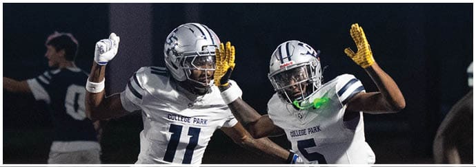 People in football uniforms are engaged in a play on a field with one person running while others attempt to block or tackle. Descripci n generada con IA