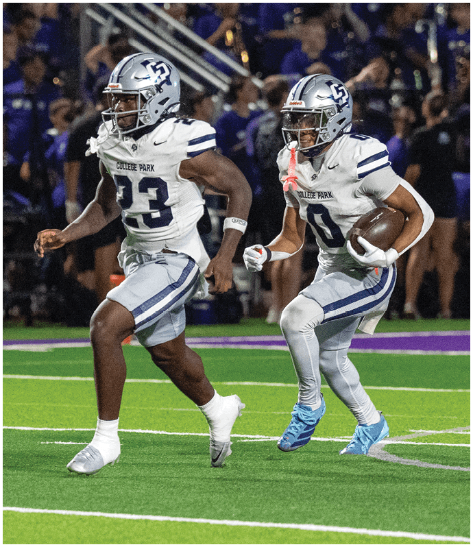 A person in a blue football uniform and helmet is on a field with another person reaching out a gloved hand in the background near a referee and blurred spectators. Descripci n generada con IA