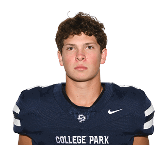 A person with short curly hair wearing a dark blue football jersey with the number 6 and the words College Park stands facing forward against a plain light background. Descripci n generada con IA