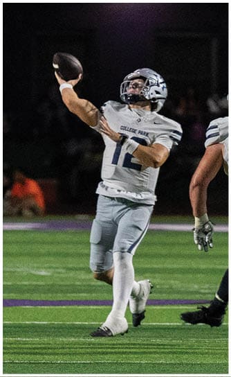 A person wearing a navy blue football uniform with the number 24 and the words College Park on the chest is on a field, wearing a white helmet with a blue stripe and a green mouthguard. Descripci n generada con IA