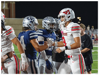 People wearing football uniforms are shaking hands on a field, suggesting a sportsmanship moment after a game. Descripci n generada con IA