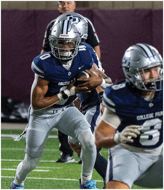 A person wearing a blue football uniform and silver helmet is holding a football and running while another person in a white cap stands in the background. Descripci n generada con IA