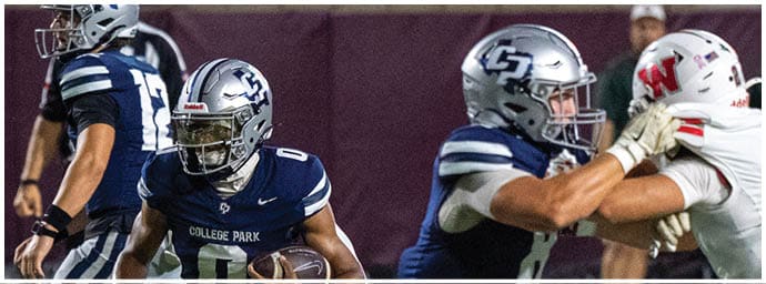 A group of football players in blue and white uniforms are actively engaged in a game on the field with one player holding the ball and others blocking opponents in white uniforms. Descripci n generada con IA