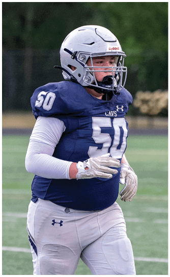 A person wearing a blue football jersey with the number 50, white long sleeves, white gloves, and a helmet is on a football field. Descripci n generada con IA