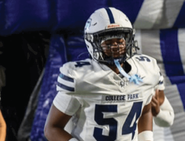A person wearing a white football uniform with the number 54 and the words “College Park" on the chest is standing on a field. Descripci n generada con IA