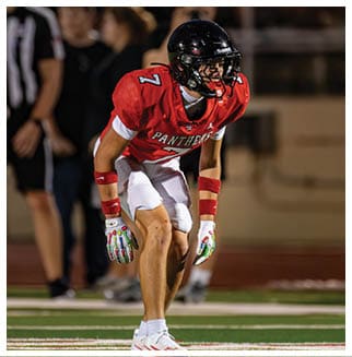 A football player wearing a blue and red jersey. Description generated by AI