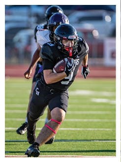 Two football players wearing black jerseys and holding hands. Description generated by AI